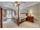 Bedroom featuring a four-poster bed, tray ceilings, neutral colors, and large windows at 413 Farm Branch Dr, Fort Mill, SC 29715
