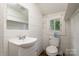 Modest bathroom with white fixtures, wood paneling, small window and practical design at 4510 Wildwood Ave, Charlotte, NC 28208