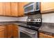 Close up of stainless steel stove, oven and microwave with dark countertops and wood cabinets at 5307 Ayers Orchard Way, Charlotte, NC 28227