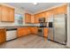 Well-lit kitchen features stainless appliances, wood cabinets, and gray wood-look laminate floors at 5307 Ayers Orchard Way, Charlotte, NC 28227