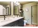Bathroom featuring double sinks, a large framed mirror, and a tiled shower with a glass door at 6425 Pamela St, Huntersville, NC 28078