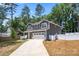 View of the property showcasing its gray siding, manicured lawn, long driveway, and a two-car garage at 6425 Pamela St, Huntersville, NC 28078