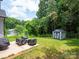 Cozy backyard patio with outdoor seating and a shed, surrounded by lush greenery and mature trees at 720 4Th St, Stanley, NC 28164