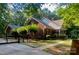 Exterior side view of the red brick home with mature trees, a fenced yard, and side porch at 7408 Mockingbird Ln, Waxhaw, NC 28173