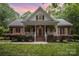 Charming home with brick facade, front porch, lush landscaping, and manicured lawn creating curb appeal at 7408 Mockingbird Ln, Waxhaw, NC 28173