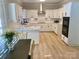 Stylish eat-in kitchen features all-white cabinetry, stainless steel appliances, and wood flooring at 7408 Mockingbird Ln, Waxhaw, NC 28173