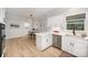 Bright kitchen boasts white cabinets, stainless appliances, and quartz counters with modern lighting and eat-in dining area at 7408 Mockingbird Ln, Waxhaw, NC 28173