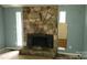 Living room view with stone fireplace, windows, showing damaged floors and blue walls at 7705 Stone Canyon Ln, Charlotte, NC 28227