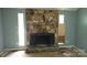 Living room view with stone fireplace and windows, showing damaged floors and blue walls at 7705 Stone Canyon Ln, Charlotte, NC 28227