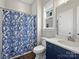 Cozy bathroom with a blue floral shower curtain, and single sink vanity with a blue cabinet at 822 River Oaks Ln, Charlotte, NC 28226