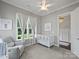Bright Bedroom featuring a white crib, comfortable glider, and natural light from a large window at 822 River Oaks Ln, Charlotte, NC 28226