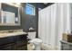 Dark bathroom with granite countertop, silver framed mirror and patterned shower curtain at 8427 Penton Pl, Harrisburg, NC 28075