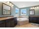 Elegant bathroom with a large soaking tub, dual vanities, and stylish mirrors at 8427 Penton Pl, Harrisburg, NC 28075