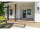 Covered front porch with wooden pillars, brick steps, and decorative landscaping at 1010 Oneil Dr, Monroe, NC 28112