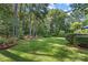 Expansive backyard with lush green grass, mature trees, and landscaping beds along the brick retaining wall at 1069 Westlake Dr, Kannapolis, NC 28081