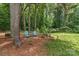 Secluded backyard sitting area with two Adirondack chairs and a small table, nestled among mature trees and pine straw at 1069 Westlake Dr, Kannapolis, NC 28081