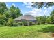 Well-manicured backyard featuring a brick house, lush green lawn, mature trees, and a patio with an umbrella for outdoor relaxation at 1069 Westlake Dr, Kannapolis, NC 28081