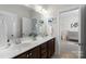 Bathroom with double sinks, white countertops, and a glimpse into an adjacent Bedroom at 11806 Stirling Field Dr, Pineville, NC 28134