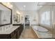 Elegant bathroom featuring double vanities, soaking tub, and a glimpse into the main bedroom at 11806 Stirling Field Dr, Pineville, NC 28134
