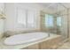 Bright bathroom with a soaking tub near a window, plus a tiled shower with glass door at 11806 Stirling Field Dr, Pineville, NC 28134