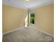 A comfortable bedroom with neutral walls, carpet, and a window overlooking greenery at 13419 Morgan Lee Ave, Charlotte, NC 28213