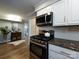 Kitchen with stainless steel appliances and granite countertops view from adjoining room with hardwood floors and neutral paint at 1708 Roxborough Rd # C, Charlotte, NC 28211