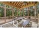 This screened-in patio features wooden furniture, a ceiling fan, and beautiful views of the surrounding trees at 177 Yadkin Falls Rd, New London, NC 28127