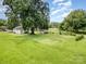 Wide shot showing a house with a large, grassy backyard, mature trees, and a small outbuilding at 201 Oakland Dr, Lowell, NC 28098