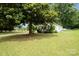 A cozy, light-colored house nestled among lush trees in a grassy yard at 201 Oakland Dr, Lowell, NC 28098