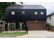 Contemporary two-story black home with a metal roof, brown garage door, and manicured front yard at 2107 W Trade St, Charlotte, NC 28216