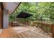 Inviting wood deck with outdoor seating and umbrella, nestled among mature trees at 307 E Allenton St, Mount Gilead, NC 27306