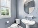 Bathroom featuring pedestal sink, toilet and large window with plantation shutters at 4536 Rustling Woods Dr, Denver, NC 28037