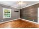 Bedroom with wood panel accent wall, hardwood floors, ceiling fan, and large window at 4536 Rustling Woods Dr, Denver, NC 28037