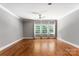 Spacious bedroom with hardwood floors, neutral paint, crown molding, ceiling fan and large windows providing natural light at 4536 Rustling Woods Dr, Denver, NC 28037