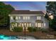 An exterior elevation showcasing a well-lit backyard, patio with pergola, and stunning pool at twilight at 4536 Rustling Woods Dr, Denver, NC 28037