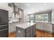 Elegant kitchen featuring white cabinets, stainless steel appliances, and a central island with countertop seating at 4536 Rustling Woods Dr, Denver, NC 28037