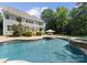 Resort-style pool with lush landscaping, a stone waterfall, and an umbrella table for outdoor relaxation at 4536 Rustling Woods Dr, Denver, NC 28037