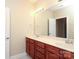 Bathroom with double sink vanity with wood cabinets, tile floor, and large mirror at 458 Leaf Arbor Ct, Clover, SC 29710