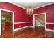 Formal dining room with rich red walls, hardwood floors, and a decorative chandelier at 458 Leaf Arbor Ct, Clover, SC 29710