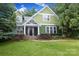 Charming two-story green home with a stone-accented front porch and lush landscaping at 458 Leaf Arbor Ct, Clover, SC 29710