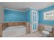Bright bathroom with a tiled bathtub, blue walls, white door and modern toilet at 7011 S Providence Rd, Waxhaw, NC 28173