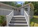Back porch exterior shot, showcasing the house's entrance with gray siding, a white deck, white rails, and mature trees at 7011 S Providence Rd, Waxhaw, NC 28173