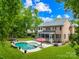 Beautiful backyard featuring a pool, a screened porch, a patio with lounge chairs, and lush green landscaping at 7229 Olde Sycamore Dr, Mint Hill, NC 28227