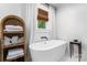 Bright bathroom with a freestanding tub, window, white curtain, and woven shelf for linens at 772 Eden Ter, Rock Hill, SC 29730