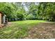 Spacious backyard featuring a mix of grass and bare earth, surrounded by mature trees and foliage at 822 Cantwell St, Charlotte, NC 28208