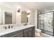 Bathroom with a double vanity, arch mirrors, modern light fixtures, and a glass shower with marble-look tile at 9410 Mountain Aire Cir, Charlotte, NC 28214