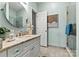 Bright bathroom includes a vanity with stone countertop, a decorative mirror, and tiled shower at 1007 Southwest Dr, Davidson, NC 28036