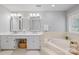 Bright bathroom with double sink vanity, soaking tub, tile floors and a large window at 10918 Megwood Dr, Charlotte, NC 28277