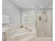 Beautiful bathroom features soaking tub, tiled shower with glass door, and a large window at 10918 Megwood Dr, Charlotte, NC 28277