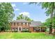 Beautiful two-story brick home with lush green lawn and mature trees at 10918 Megwood Dr, Charlotte, NC 28277